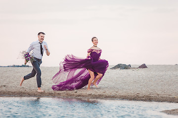 Image showing Young romantic couple running on the beach of sea