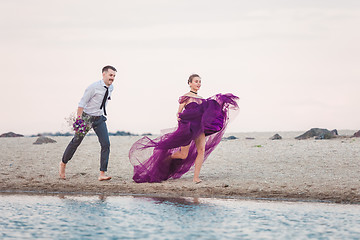 Image showing Young romantic couple running on the beach of sea