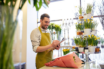 Image showing florist man with clipboard at flower shop counter