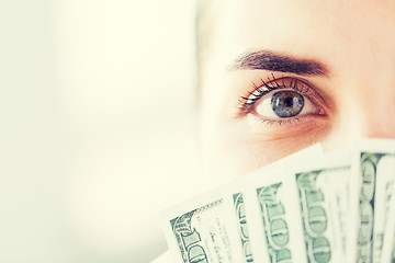 Image showing woman hiding her face behind us dollar money fan