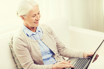 Image showing happy senior woman with laptop at home