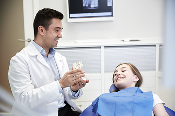 Image showing happy dentist showing jaw layout to patient girl