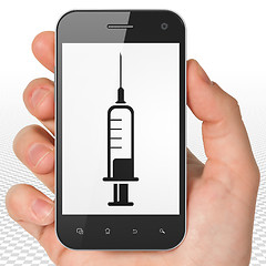Image showing Health concept: Hand Holding Smartphone with Syringe on display