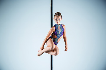 Image showing The strong and graceful young girl performing acrobatic exercises on pylon