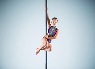 Image showing The strong and graceful young girl performing acrobatic exercises on pylon