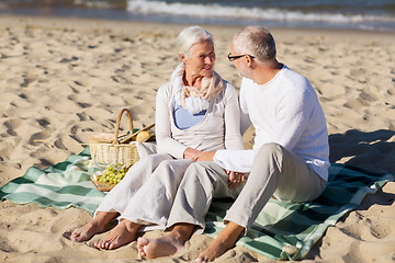 Image showing happy senior couple having picnic on summer beach