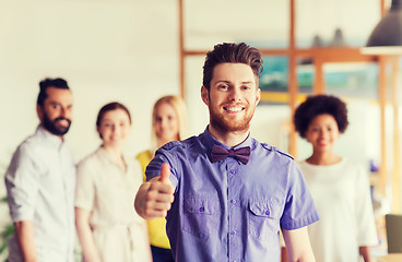 Image showing happy man showing thumbs up over team in office