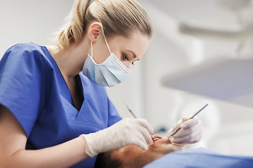 Image showing female dentist checking up male patient teeth
