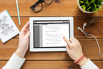 Image showing close up of woman with tablet pc on wooden table