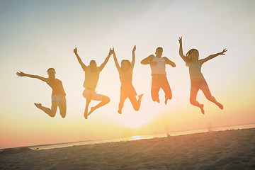 Image showing smiling friends dancing and jumping on beach