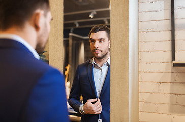 Image showing man trying jacket on at mirror in clothing store