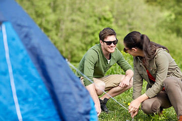 Image showing happy couple setting up tent outdoors