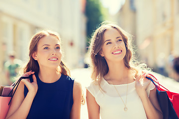 Image showing happy women with shopping bags walking in city 