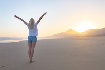 Image showing Free woman enjoying freedom on beach at sunrise.