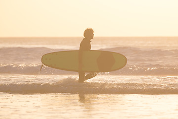 Image showing Silhouette of surfer on beach with surfboard.