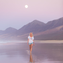 Image showing Lady walking on sandy beach in sunset.