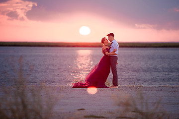 Image showing Young romantic couple relaxing on the beach watching the sunset