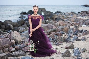 Image showing Young romantic woman posing on the beach watching the sunset