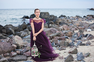 Image showing Young romantic woman posing on the beach watching the sunset