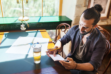 Image showing man with beer writing to notebook at bar or pub