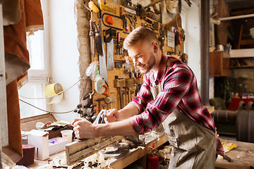 Image showing carpenter working with plane and wood at workshop