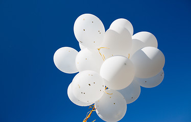 Image showing close up of white helium balloons in blue sky