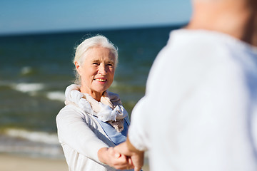 Image showing happy senior couple holding hands on summer beach