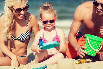 Image showing happy family playing with sand toys on beach