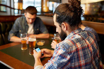 Image showing close up of men with smartphones and beer at bar