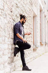 Image showing man texting message on smartphone at stone wall