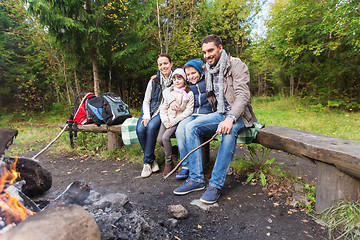 Image showing happy family sitting on bench at camp fire