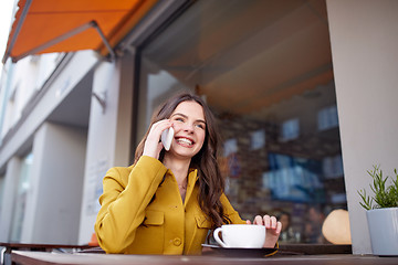 Image showing happy woman calling on smartphone at city cafe