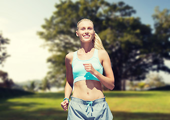 Image showing smiling young woman running or jogging over park