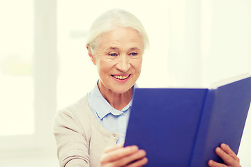 Image showing happy smiling senior woman reading book at home