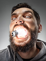 Image showing Caucasian man with bulb in his mouth on gray background