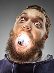 Image showing Caucasian man with bulb in his mouth on gray background