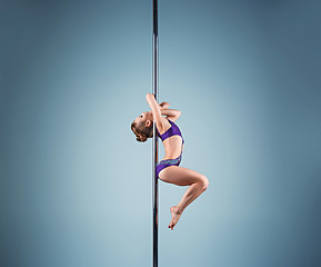Image showing The strong and graceful young girl performing acrobatic exercises on pylon