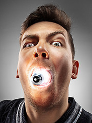 Image showing Caucasian man with bulb in his mouth on gray background