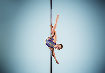 Image showing The strong and graceful young girl performing acrobatic exercises on pylon