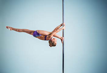 Image showing The strong and graceful young girl performing acrobatic exercises on pylon