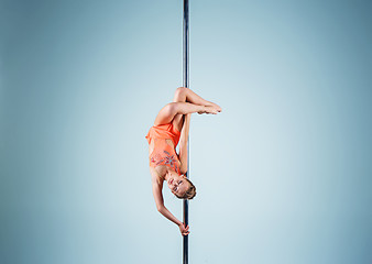 Image showing The strong and graceful young girl performing acrobatic exercises on pylon