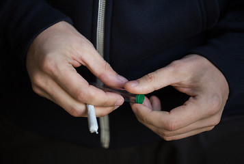 Image showing close up of addict hands with marijuana joint tube