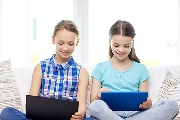 Image showing happy girls with tablet pc sitting on sofa at home