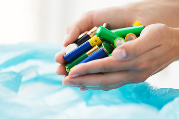 Image showing close up of hands putting batteries to rubbish bag