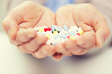 Image showing close up of senior woman hands with pills