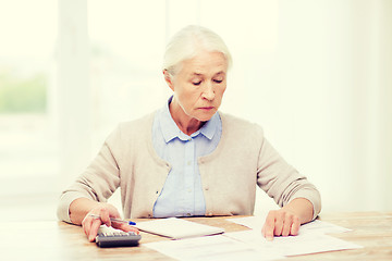 Image showing senior woman with papers and calculator at home