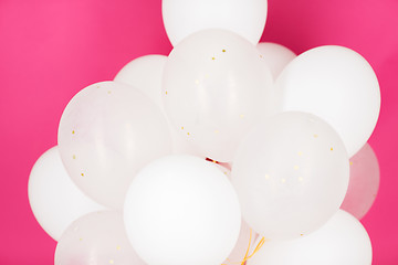 Image showing close up of white helium balloons over pink