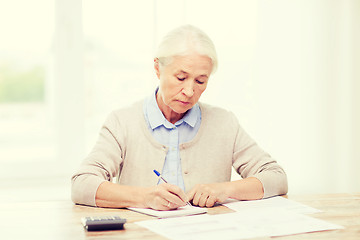 Image showing senior woman with papers and calculator at home