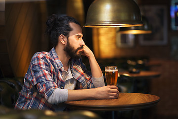 Image showing unhappy lonely man drinking beer at bar or pub