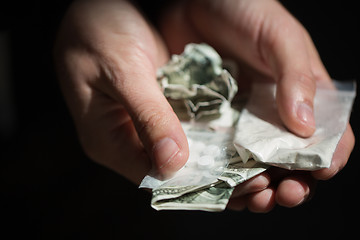 Image showing close up of addict hands with drugs and money